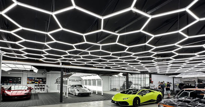 Detailing showroom with a full hexagon light ceiling above supercars