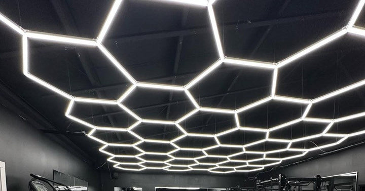 Hexagon light grid across the dark ceiling of a gym with racks and training equipment