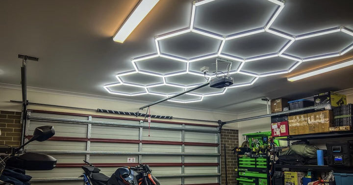 Cool white hexagon lights on a garage ceiling above a motorbike and storage shelves